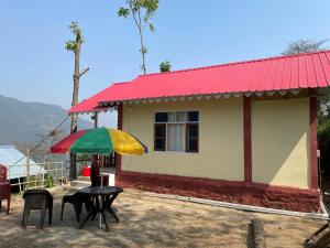 a small house with a table with a colorful umbrella at Kolakham Hillcrest Homestay in Rishop