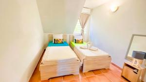 um pequeno quarto com 2 camas e um espelho em Magnifique Appartement Fleurs Caraïbes - 6 personnes en résidence avec piscine privée - Sainte Anne em Sainte-Anne