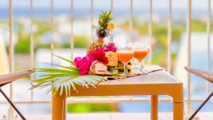 uma mesa com copos de sumo de laranja e flores em Magnifique Appartement Fleurs Caraïbes - 6 personnes en résidence avec piscine privée - Sainte Anne em Sainte-Anne