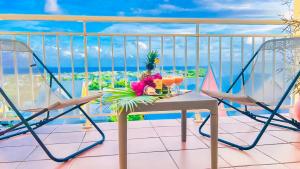 uma mesa e cadeiras numa varanda com vista para o oceano em Magnifique Appartement Fleurs Caraïbes - 6 personnes en résidence avec piscine privée - Sainte Anne em Sainte-Anne