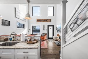 a kitchen with white cabinets and a staircase with windows at Stella Boona Loft Traverse close to Trail and beach in Traverse City