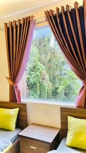 een kamer met 2 bedden en een raam met gordijnen bij Uyên House hotel in Da Lat
