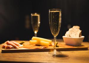 uma mesa com um prato de queijo e duas taças de champanhe em Le Refuge Bleu em Famars