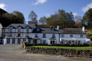 a large white building with a stone wall at The Inn on Loch Lomond in Luss