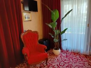 a red chair and a plant in a room at GRAND HOTEL LE FONTI in Chianciano Terme