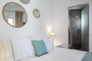 a bedroom with a white bed and a mirror at Colours of Mykonos Luxury Residences & Suites in Psarou