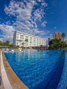 a large swimming pool in front of a hotel at Tamaca Beach Resort in Santa Marta