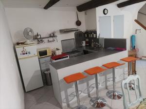 a kitchen with a counter with orange bar stools at La petite Corbières in Roquefort-des-Corbières