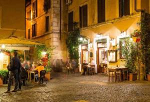 Un groupe de personnes assises à des tables dans une rue la nuit dans l'établissement Casa Cecilia Roma, à Rome