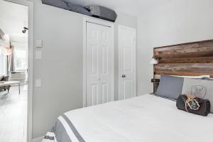 une chambre avec un lit blanc avec une tête de lit en bois dans l'établissement Chouette A - Mont-Tremblant, à Mont-Tremblant