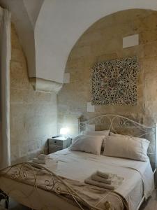um quarto com uma cama branca e uma parede de pedra em Il Vico em Lecce