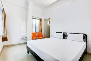 um quarto com uma grande cama branca e uma cadeira laranja em Super OYO Hotel Goverdhan Villa em Udaipur