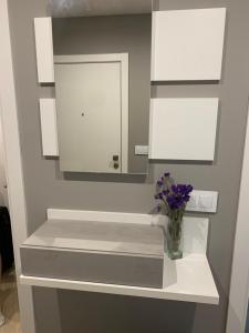 - une salle de bains blanche avec un vase de fleurs violettes sur une étagère dans l'établissement Acogedor apartamento en Baiona, à Baiona