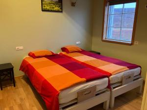 a bedroom with a bed with an orange and red comforter at Fagrafell Hostel in Husavik