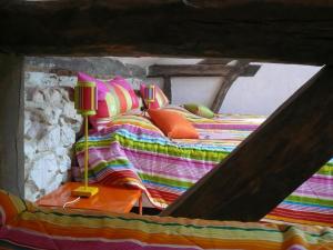 a bed with colorful blankets and pillows in a room at La tour du guet in Arouille