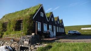 ein schwarzes Haus mit einem Grasdach auf einem Hügel in der Unterkunft Fagrafell Hostel in Skogar