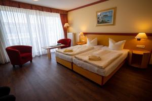 ein Hotelzimmer mit einem großen Bett und einem roten Stuhl in der Unterkunft Hotel Esplanade & Aparthotel Rialto in Binz