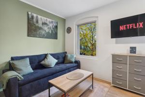 a living room with a blue couch and a window at Vorstadtoase - 3 Personen - Apartment mit Queensize-Bett, Badewanne, Schlafcouch, Parken, Netflix, Nähe BER in Eichwalde