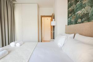 Un dormitorio con una cama blanca con toallas. en Peroulia Beach Houses, en Koroni