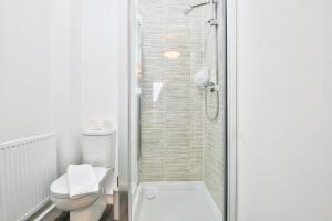 a white bathroom with a shower and a toilet at StayRight 2 Bedroom Flat with Private Parking on Waterfront in Barry