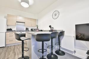 a kitchen with two bar stools and a counter at StayRight 2 Bedroom Flat with Private Parking on Waterfront in Barry