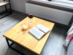 - une table en bois avec un verre de vin et un livre dans l'établissement Cozy apartment in a complex Semycvit, à Lviv