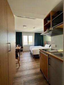 een hotelkamer met een bed en een keuken met een wastafel bij AMH - Wohnen auf Zeit in München