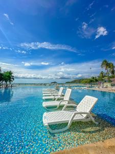 - une rangée de chaises longues dans une piscine dans l'établissement Tamaca Beach Resort, à Santa Marta