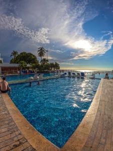 a large swimming pool with people in the water at Tamaca Beach Resort in Santa Marta