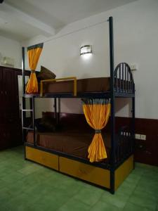 2 Etagenbetten mit orangefarbenen Vorhängen in einem Zimmer in der Unterkunft Hosteller's in Varkala