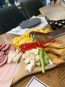 una tabla de cortar con carnes y hortalizas sobre una mesa en Hotel Muntele Mic en Borlova