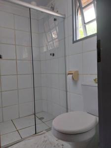 a bathroom with a toilet and a glass shower at Circular Guest House in Itacaré
