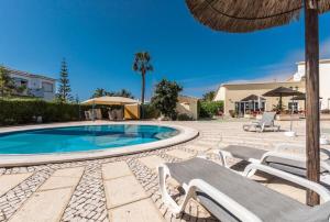 a swimming pool with two lounge chairs and an umbrella at 2 Bedroom Top Floor Apartment, Oasis Parque, near Alvor AT01 in Portimão