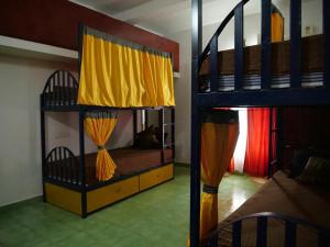 a bedroom with two bunk beds with yellow curtains at Hosteller's in Varkala