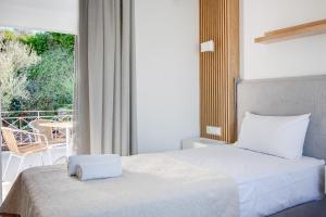 a bedroom with a white bed and a balcony at Peroulia Beach Houses in Koroni