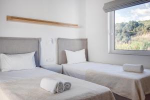 2 camas en una habitación blanca con ventana en Peroulia Beach Houses, en Koroni