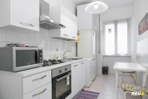 a white kitchen with a microwave and a sink at Piazza Bologna Holiday House in Rome