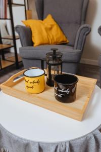 duas chávenas sentadas numa bandeja de madeira sobre uma mesa em Apartamenti Katrīna em Brocēni