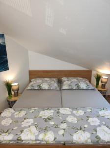 a bed with a bedspread with white flowers on it at Wellness apartmán s vířivkou a saunou in Plzeň
