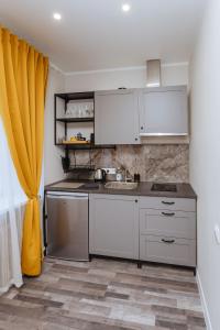 a kitchen with white cabinets and a yellow curtain at Apartamenti Katrīna in Brocēni
