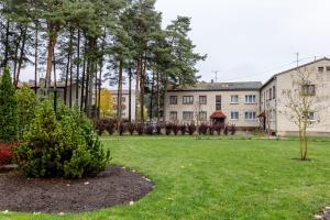 a yard with trees and a building in the background at Apartment Katrina in Brocēni