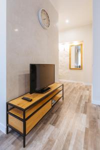 a living room with a television and a clock on the wall at Apartamenti Katrīna in Brocēni