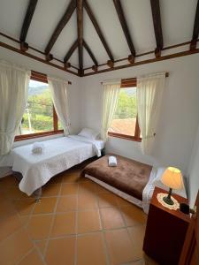 duas camas num quarto com duas janelas em Refugio Khalma de la Montaña em Villa de Leyva