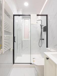 uma casa de banho branca com um chuveiro e um WC. em Céntrico Apartamento Vigo- Oporto Luxury em Vigo
