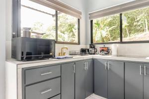 a kitchen with gray cabinets and a microwave at Villas Anna Bertha in San Isidro de El General