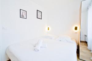 Schlafzimmer mit einem weißen Bett und einem Spiegel in der Unterkunft Le Gustave Eiffel - Porte d'Orléans in Gentilly