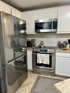 una cocina con electrodomésticos de acero inoxidable y armarios blancos en New Remodel Shuttle to AF Resort, en Angel Fire