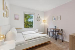 a white bedroom with a bed and a table at Vorstadtoase für 2 - Netflix, Parkplatz, Nähe BER, Queensize-Bett in Eichwalde