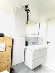 a white bathroom with a sink and a mirror at Coast House 25 -TRZĘSACZ SUNNY SIDE BALTIC in Trzęsacz