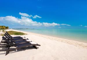 a row of lounge chairs sitting on a beach at Clevelander in Long Bay Hills
